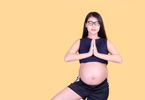 hermosas mujeres asiáticas embarazadas se paran en el suelo y se relajan con ejercicios de yoga foto