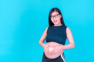 A beautiful pregnant Asian woman applies a cream to her abdomen to prevent stretch marks photo