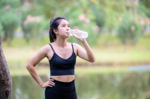 hermosas mujeres asiáticas beben agua antes de calentarse para mantener sus músculos flexibles foto