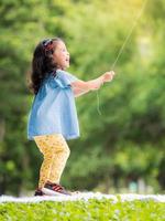 niña asiática parada en la alfombra, jugando y aprendiendo fuera de la escuela para disfrutar en el parque natural foto