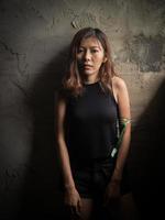 una mujer asiática adolescente se apoyó contra una pared y se tensó después de tensar los brazos para prepararse para tomar drogas foto