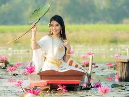 An elegant Thai woman wearing traditional Thai clothes  carrying lotus flowers leaf collected from a lotus field photo