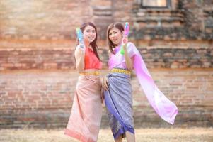 Beautiful Asian women hold plastic water guns at an ancient temple during Songkran, the most beautiful and fun water festival in Thailand photo