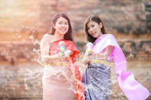 Beautiful Asian women hold plastic water guns at an ancient temple during Songkran, the most beautiful and fun water festival in Thailand