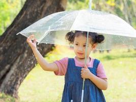 una niña estaba felizmente parada en un paraguas contra la lluvia foto