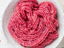 Mince beef, ground meat with ingredients for cooking on white wooden rustic table photo