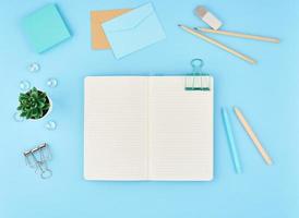 Blank notepad page for text on blue office desktop. Top view of modern bright table with notebook photo