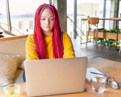 concepto de nómada digital. chica independiente que trabaja de forma remota en una computadora portátil en un café, coworking.