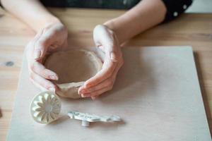Woman making pottery, hands closeup, blurred background, focus on potters, palms with pottery. Turning passion into a job photo