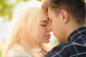 A man affectionately call looks at woman, guy and girl are worth close, touching tips noses. Concept of first teenage love and first kiss. Boy and girl, couple. Intimacy, honesty, trust, open feelings