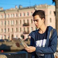 young man standing on street of a big city and looking at a guide, a tourist in St. Petersburg got lost his way photo