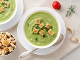 Two large white bowl with vegetable green cream soup of broccoli, zucchini, green peas photo