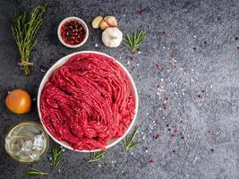 Mince beef, ground meat with ingredients for cooking on dark blue photo
