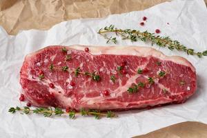 Big whole piece of raw beef meat, striploin on white parchment paper photo