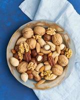 Classic blue in food. Mix of nuts on plate - walnut, almonds, pecans, macadamia photo