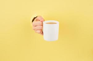 persona irreconocible sosteniendo una taza de té con fondo amarillo, espacio de copia cerrado foto