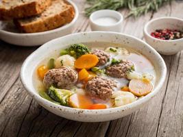 meatballs soup in white plate on old wooden rustic grey table, side view photo