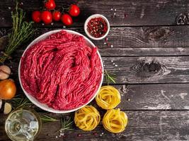 Mince beef, ground meat with ingredients for cooking on dark blue photo