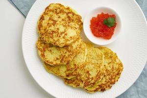 Zucchini pancakes with potato and red caviar, fodmap keto diet top view closeup