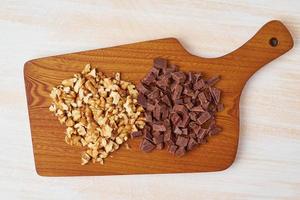 Chopped walnuts and chocolate on wooden board. Step by step recipe for Banana bread.