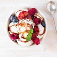 Balls of vanilla ice cream in mug with raspberry and blueberries photo