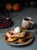 Belgian waffles with raspberries, chocolate syrup. Breakfast with tea on dark background