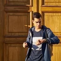 adulto joven mira el reloj. hombre caucásico estresado con cabello negro con miedo de llegar tarde. la chica llega tarde a una cita foto