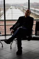 Train Station. A mature man in business clothes and a coat is sitting in a waiting room photo