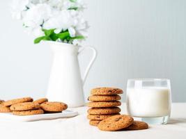 galletas de avena con chocolate y leche en vaso, merienda saludable. fondo claro, pared de luz gris