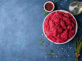 Mince beef, ground meat with ingredients for cooking on dark blue photo