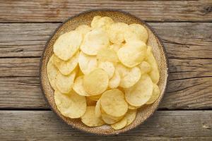 crisp in bowl, wooden background, top view photo