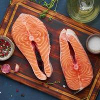 Two salmon steaks, fish fillet, large sliced portions on chopping board