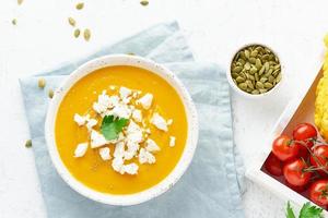 Pumpkin cream soup with feta cheese, autumn homemade food, white background, top view photo