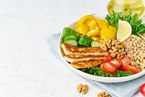 Buddha bowl with halloumi, quinoa, salad lettuce, vegetarian menu, white background, closeup with copy space photo