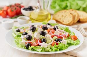 Greek salad on white plate on old rustic white wooden table, fresh salad with tomatoes, photo