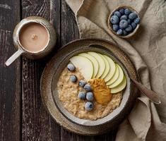 avena, papilla saludable en un tazón grande con frutas y bayas para el desayuno, taza de cacao. foto