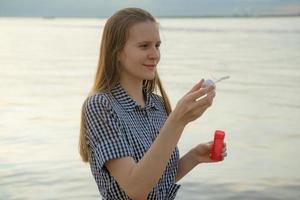 Young girl blow soup bubbles on the beach, concept of fun and joy