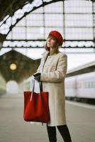 Beautiful woman is waiting for train on railway station. Girl travels light. Middle-aged female photo