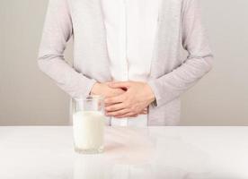 Woman next to glass of milk having bad stomach ache. photo