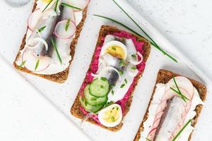 Savory smorrebrod, two traditional Danish sandwiches. Black rye bread with anchovy photo