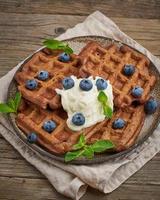 Chocolate banana waffles with blueberries, on dark wooden old table. Side view, vertical photo