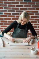 mujer sonriente feliz haciendo plato de cerámica, toque con espátula. concepto para mujer en freelance, negocios. producto artesanal. gana dinero extra, ajetreo, convirtiendo pasatiempos en dinero, pasión en trabajo foto