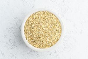 semilla de quinua en un tazón blanco sobre fondo blanco. cereales secos en taza, comida vegana, dieta fodmap foto