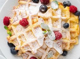 Belgian waffles with raspberries, blueberries, curd, close-up, top view photo