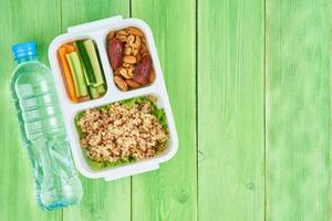 Vegan lunch box, water in bottle, green background, copy space. photo