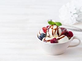 Balls of vanilla ice cream in mug with raspberry and blueberries, photo