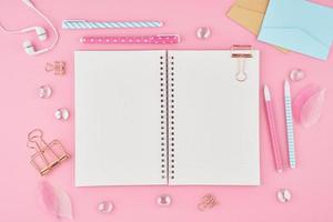 Blank notepad page in bullet journal on bright pink office desktop. Top view of modern bright table with notebook, stationery. Mock up, copy space, concept for diary photo