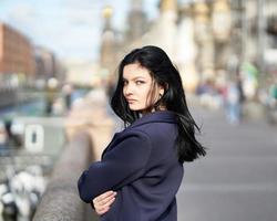 retrato f hermosa morena inteligente que camina por la calle de san petersburgo en el centro de la ciudad. encantadora mujer pensativa con cabello largo y oscuro vaga sola, inmersa en pensamientos foto