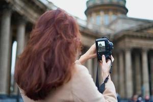 Unrecognizable person standing with his back turned and photographs sights, woman with long thick dark hair, tourist in center of St. Petersburg. Focus on camera photo