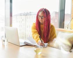 Digital nomad concept. Girl freelancer remotely working on laptop in cafe, coworking. photo